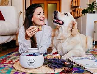 Person laying on the floor with a dog and custom imprinted snack bowl.